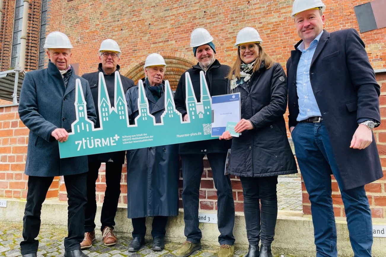 Sechs Personen halten einen Pappaufsteller der 7Türme+-Stiftung hoch