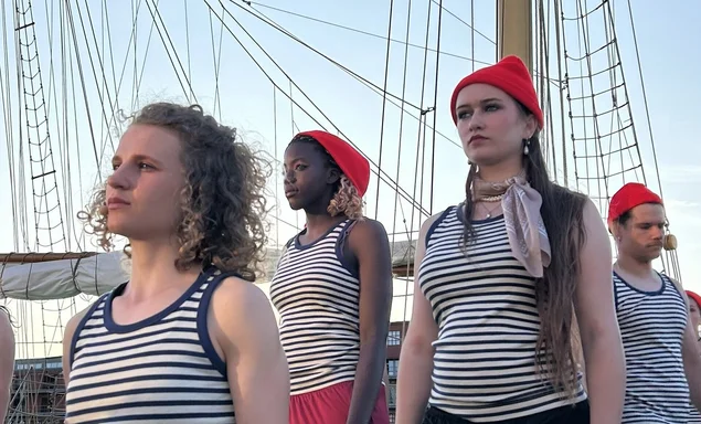 Junge Menschen in Matrosenverkleidung vor einem Segelschiff.