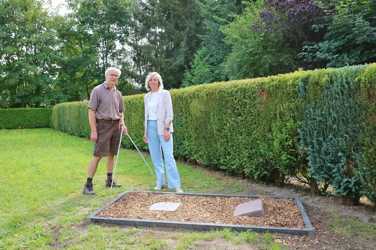 Zwei menschen stehen an einem Grab