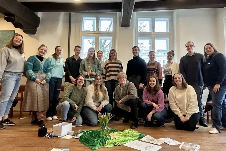 Eine Gruppe junger Menschen steht in einem Raum und schaut in die Kamera.