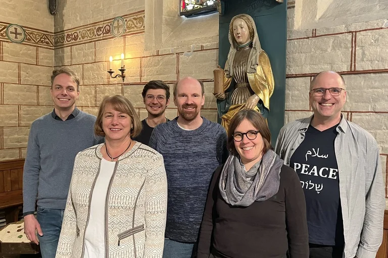 Sechs Personen stehen in einer Kirche vor einen Frauenstatue