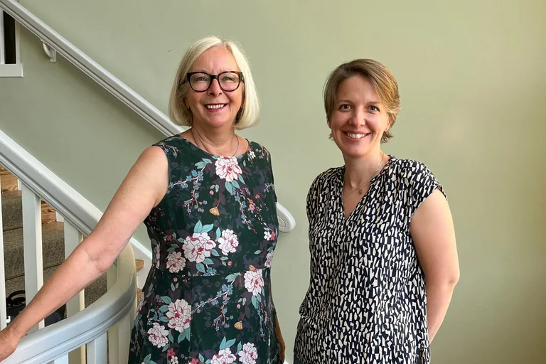 Zwei Frauen stehen an einem Treppengeländer.