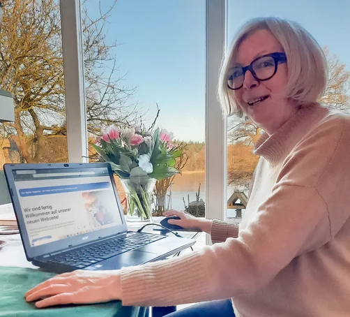 Die Synoden-Präses Katrin Thomas sitzt vor einem Laptop auf dem die neue Webseite des Kirchenkreis zu sehen ist.