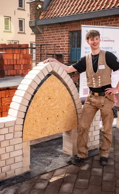 Ein junger Mann lehnt sich an das Modell eines Spitzbogens