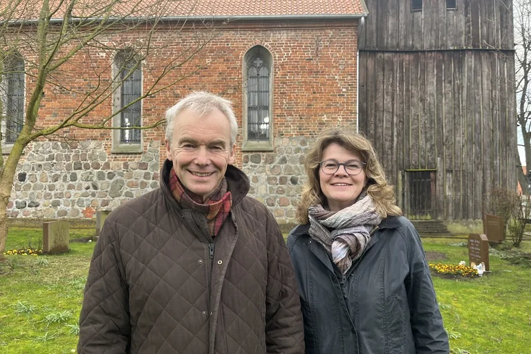 Ein Mann und eine Frau stehen draußen vor einer Kirche.