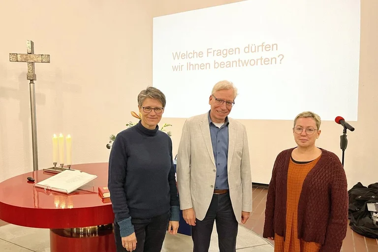 Drei Personen stehen in einer Kirche