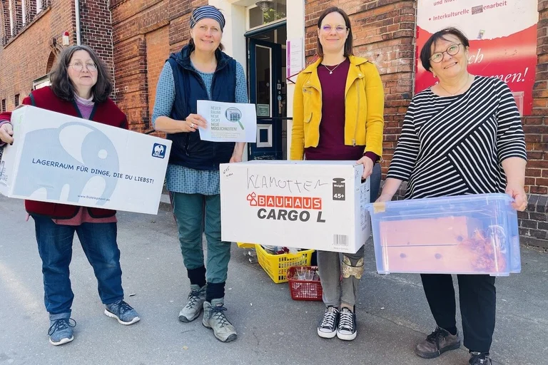 Assistentin Annette Brodderek, Leiterin Silke Meyer, Kurberaterin Saskia Lohff und Yasemin Düzen von der Interkulturellen Begegnungsstätte stehen vor dem ehemaligen Standort des Frauenwerkes mit Umzugskisten in den Händen. 