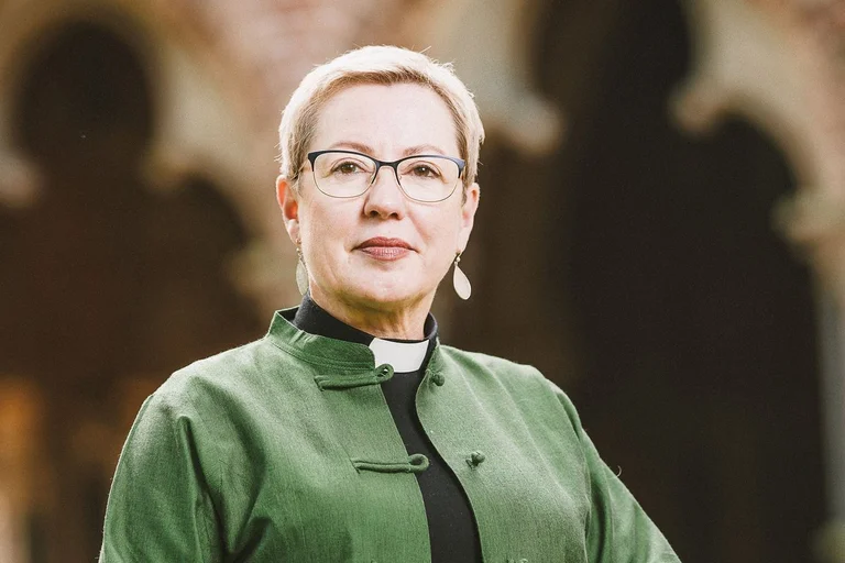 Eine Frau mit kurzen Haaren blickt ernst in die Kamera.